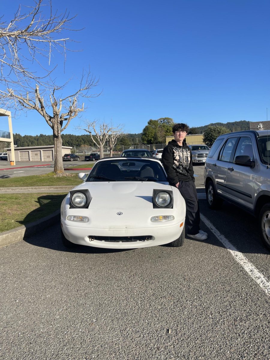 Sallin mostrando su Miata frente al estacionamiento de la escuela.